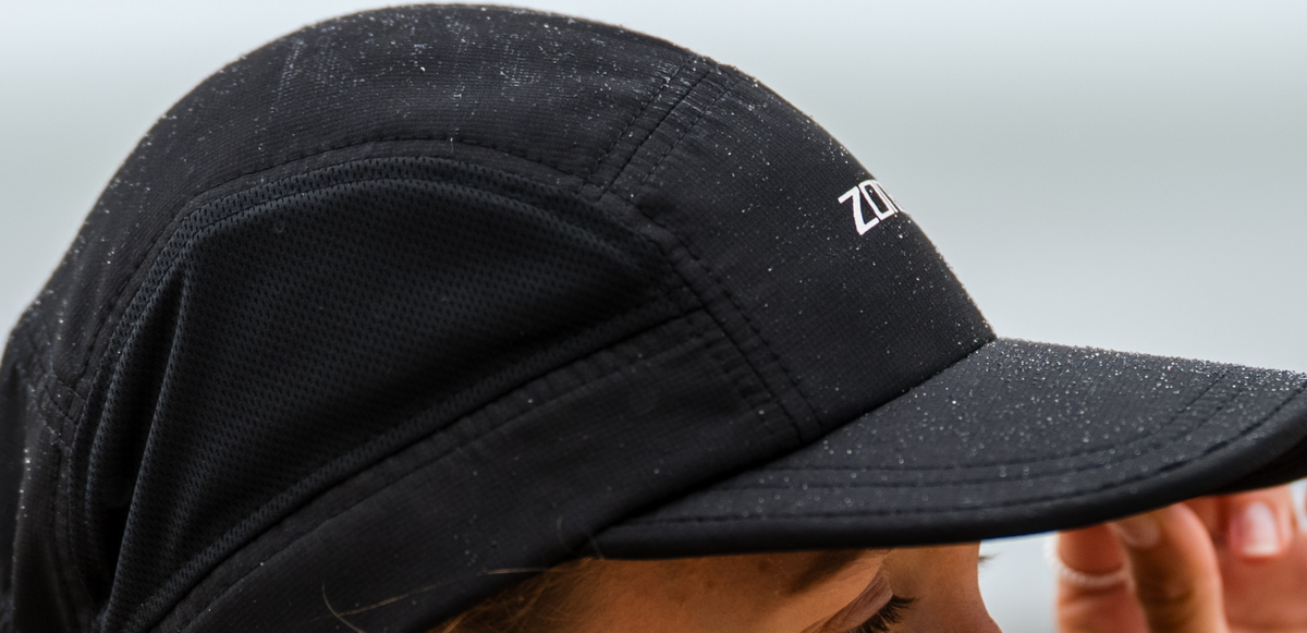 Black 5 panel running cap with zone3 logo on a blurred background