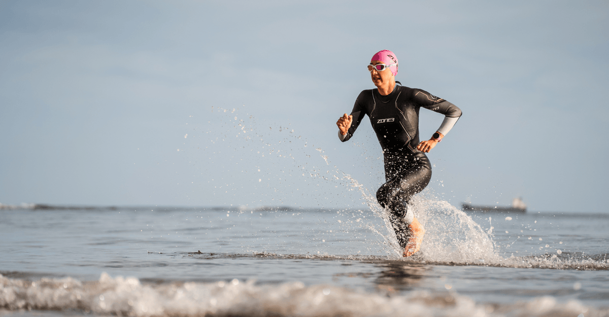 Person running out of the water on a beach with a clear sky