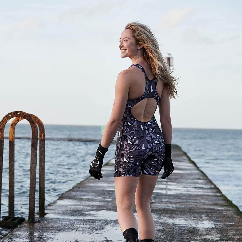 A woman wearing the Zone3 OWS Renew short leg kneeskin swimsuit on a white background.