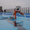 Swimmer in pool with bright orange front facing snorkel standing near the lane lines wearing a white cap and goggles