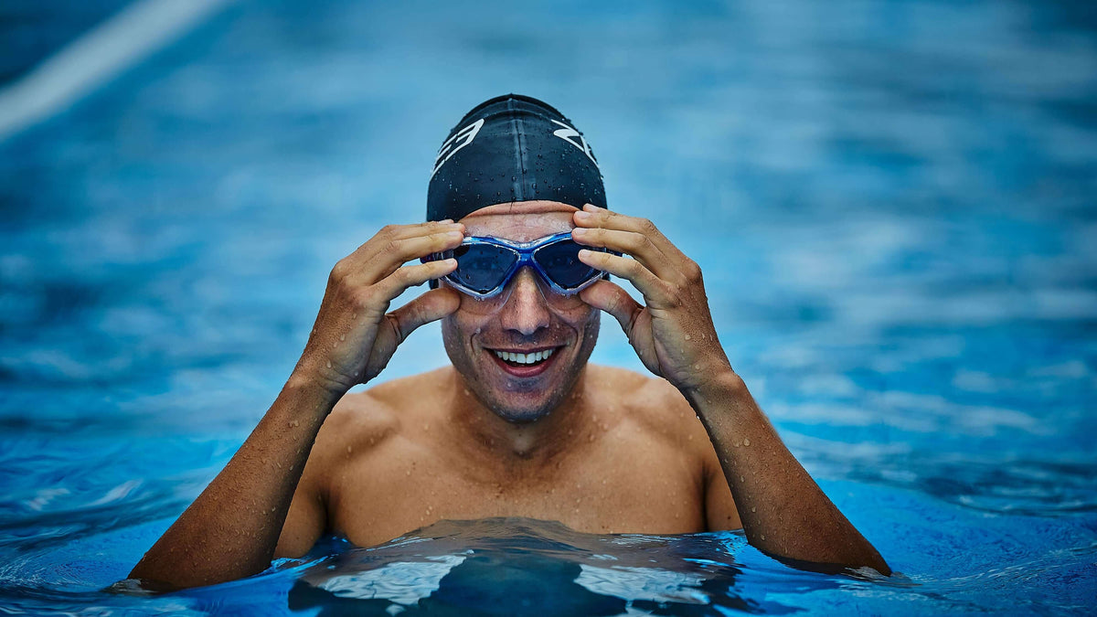 Man in a pool wearing a Zone3 swim cap and the Vision Max Clear