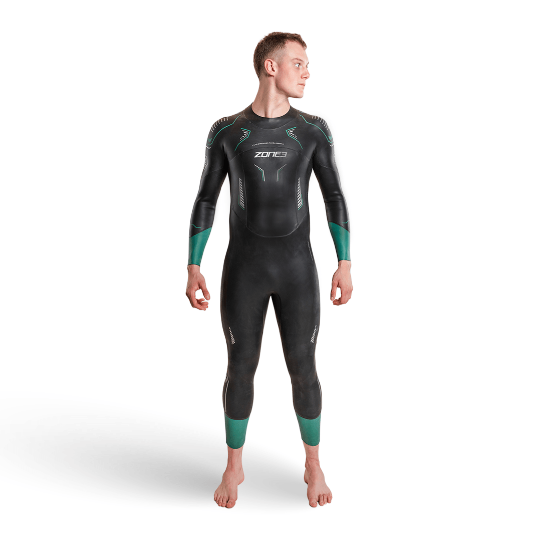 Front view of a man wearing a black Vision wetsuit with teal accents and subtle graphic panels